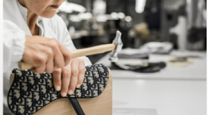 Craftsman shaping a handbag with a hammer at the workshop bench