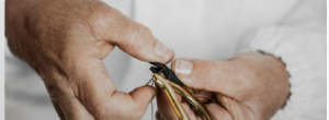 Hands finishing gold-tone hardware on a leather bag